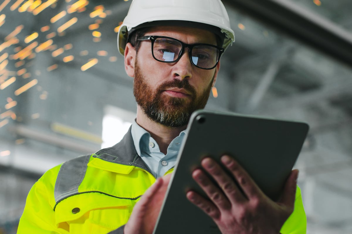 Bauleiter, der mithilfe eines Tablets vor Ort auf Projektaktualisierungen und digitale Ressourcen zugreift