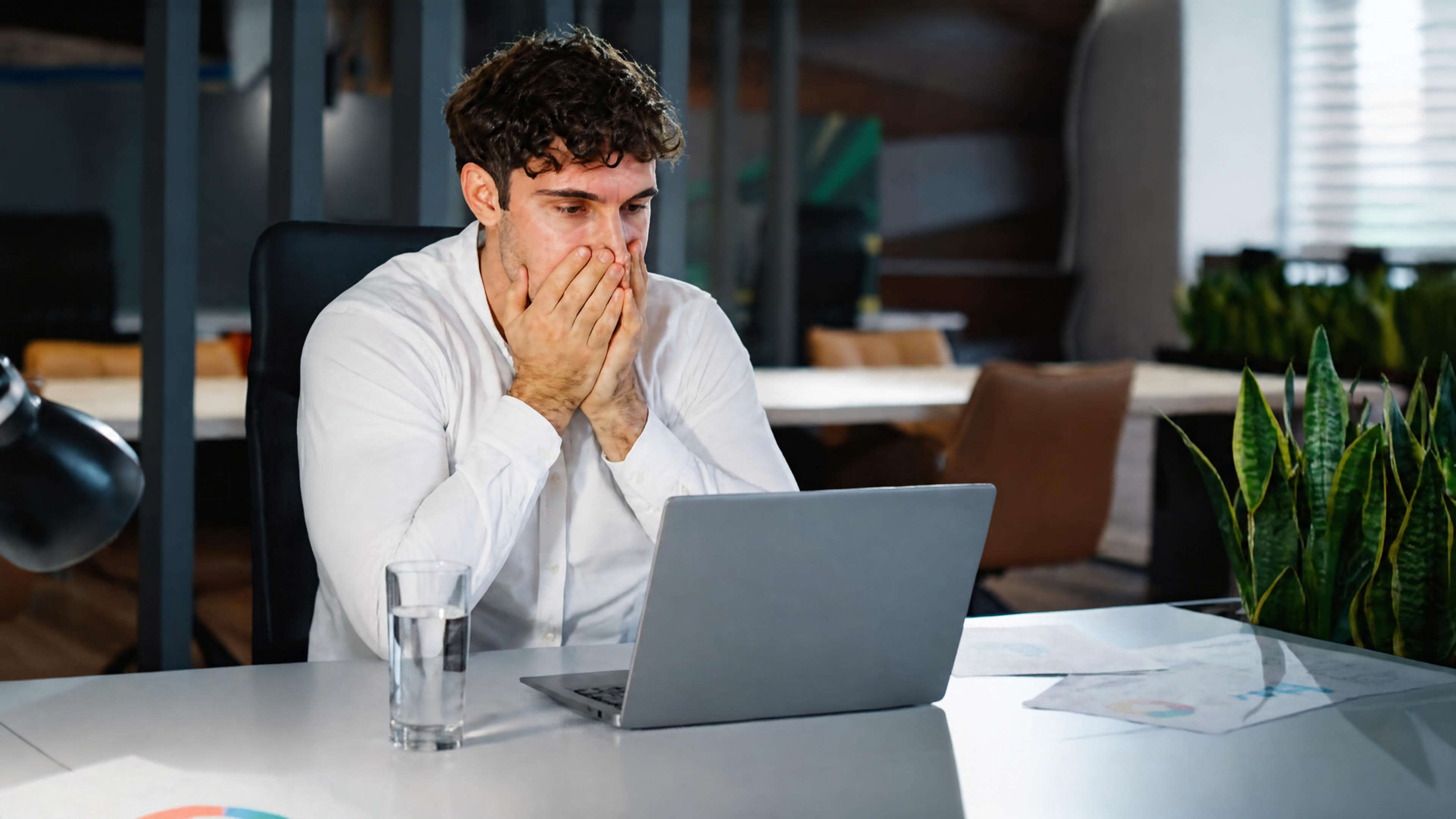 Employee looking frustrated while searching for files on a laptop