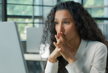 Woman looking concerned while working at a laptop