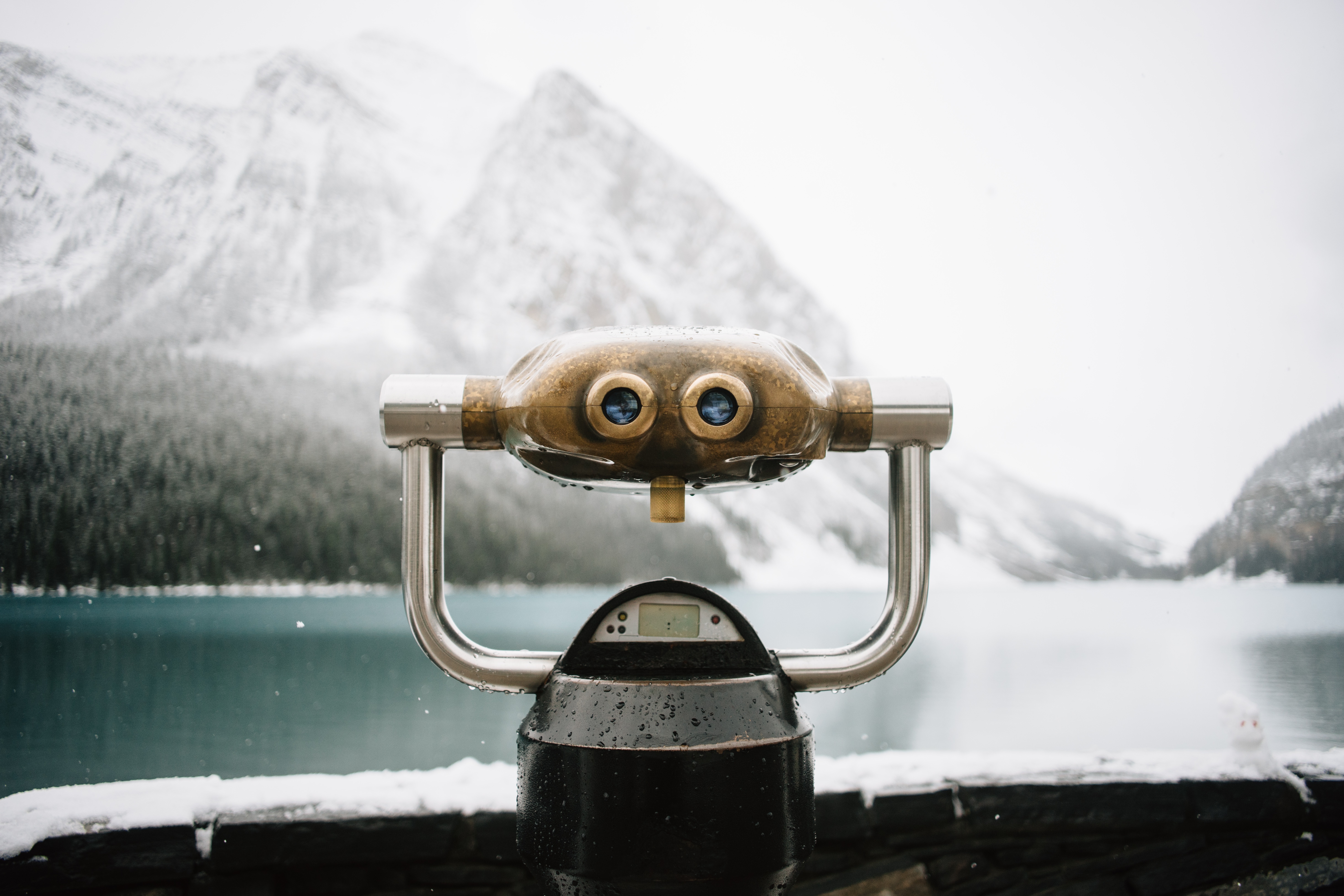 Coin-operated binocular viewer overlooking a snowy mountain lake, representing improved digital asset discovery and findability.