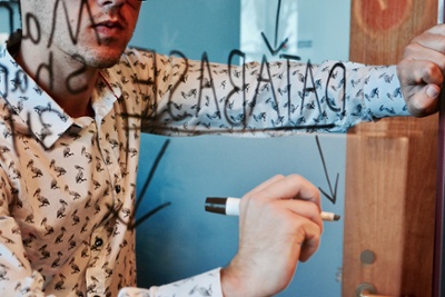Person writing on a transparent glass board while mapping a data integration workflow.
