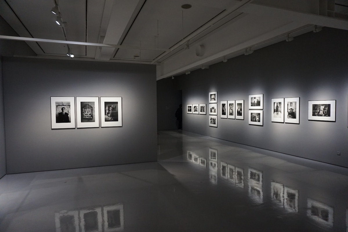 Museum photography gallery displaying framed black-and-white photographs along dark walls.