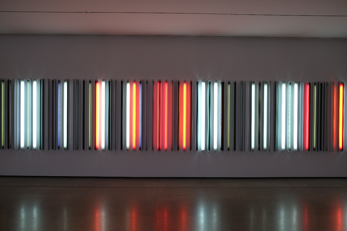 Contemporary museum gallery featuring a wall installation of colorful vertical light bars.