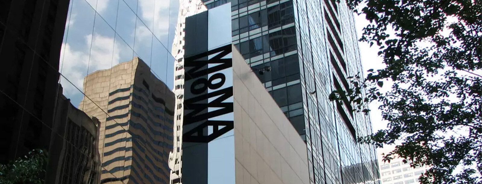 Exterior of the Museum of Modern Art (MoMA) in New York City, featuring the museum's vertical signage and modern architectural facade.