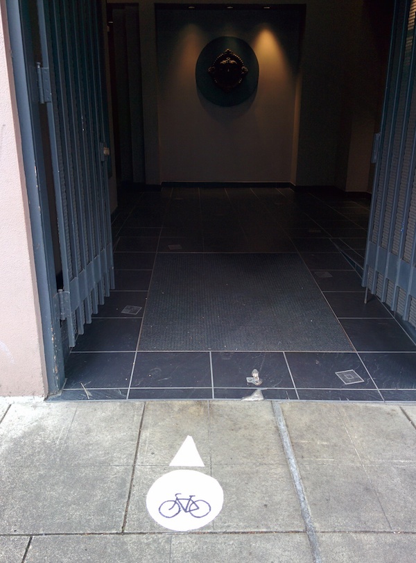 Dark tiled passageway between buildings with an open entrance, featured in an article about a downtown Portland bike path.